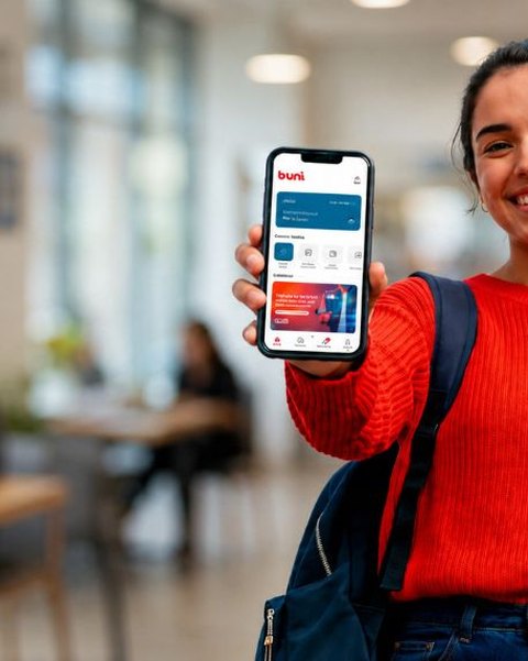Estudante sorrindo mostrando o aplicativo b.Uni no celular